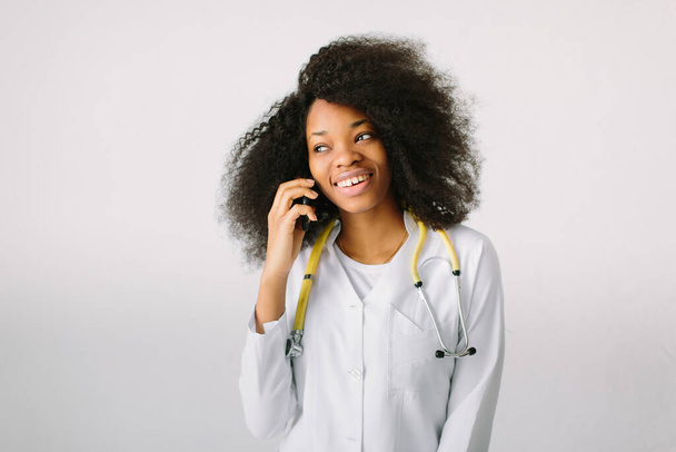 Female doctor Preparation medical equipment. An African American female medical doctor with a stethoscope in hospital on white background and talking on the phone - Foto, Imagem