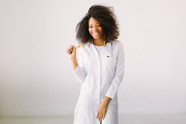 Young beautiful African American girl doctor in a white coat with a stethoscope. on white background - Zdjęcie, obraz