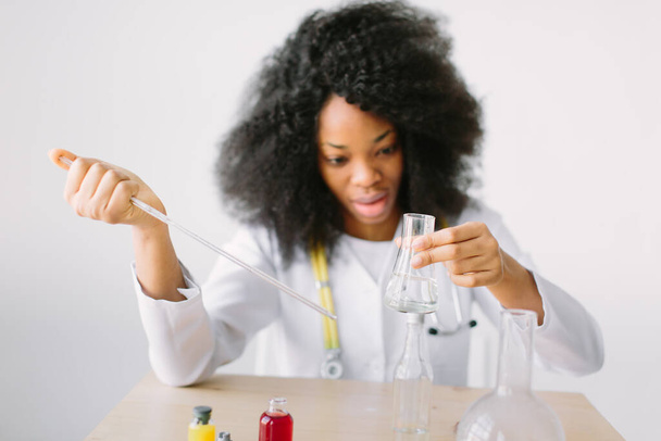 Portrait d'une jeune jeune fille afro-américaine chercheuse en chimie effectuant des recherches dans un laboratoire de chimie. Scientifique analysant une éprouvette
. - Photo, image