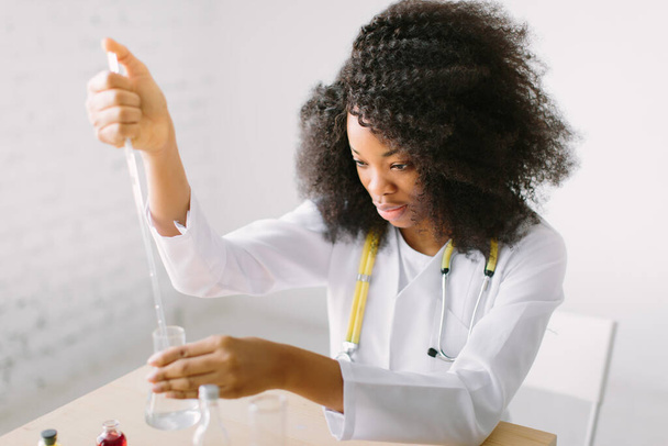 Portrait of a young beautiful African American girl researcher chemistry student carrying out research in a chemistry lab. Scientist analyzing a test-tube. - Foto, Imagem