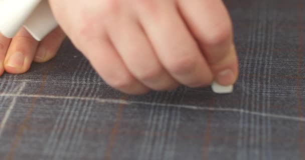 Muž kreslení domů oblek vzor s křídou na tkanině březen2020. 4K rozlišení horní pohled na výrobu oděvů v továrně na oděvy. Krejčí při práci, kreslení čáry na tkaninu s křídou. - Záběry, video