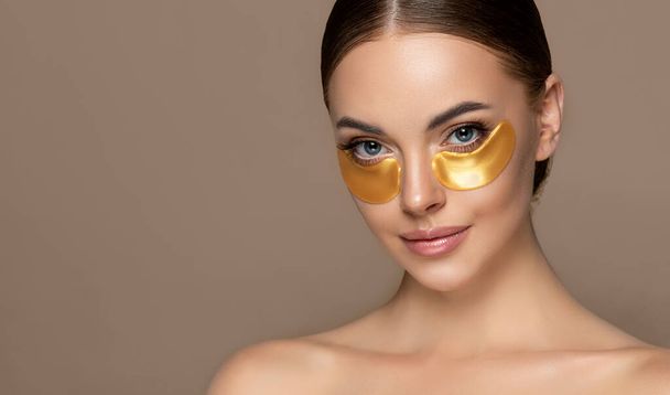 Beautiful young woman with Golden Collagen  Patches . Girl facial treatment . Cosmetology , beauty and spa . Female model, care concept - Fotografie, Obrázek