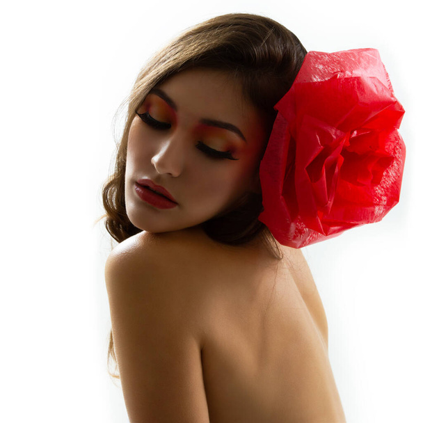 Retrato vintage de la chica glamour de la moda con flor roja en el pelo, toma de estudio. Mujer joven con hermoso maquillaje
  - Foto, imagen
