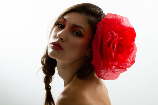 Vintage portrait of fashion glamour girl with red flower in her hair, studio shot. Young woman with beautiful make-up  - Foto, Imagem