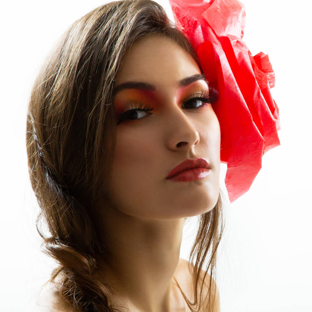Ročník portrét módní okouzlující dívka s červenou květinou ve vlasech, studio záběr. Mladá žena s krásným make-upem  - Fotografie, Obrázek
