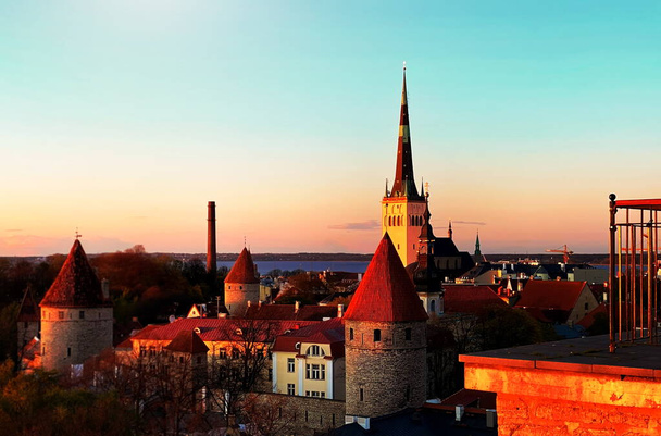 Sonnenuntergang Stadt Tallinn Altstadt rote Dächer mittelalterliches Panorama auf der Skyline Wolken blauer Himmel Sonne unten Sommerwetter Ostsee am Horizont Reise nach Estland, Besuch Europa  - Foto, Bild