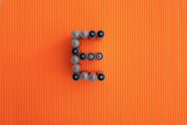 A letra E (energia) consiste em pilhas aa em um fundo laranja
 - Foto, Imagem
