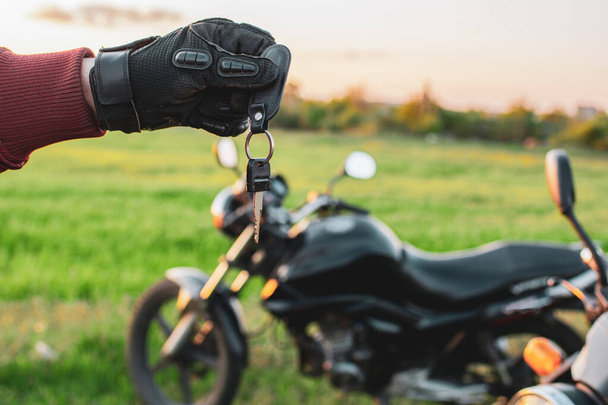 Человек, держащий ключ от темного транспорта на фоне мотоциклов
 - Фото, изображение