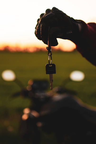 muž drží tmavý dopravní klíč na pozadí motocyklů - Fotografie, Obrázek