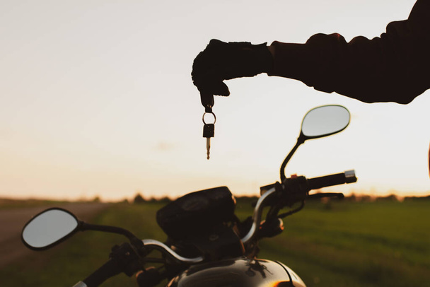 man holding a dark transport key on a background of motorcycles - Zdjęcie, obraz