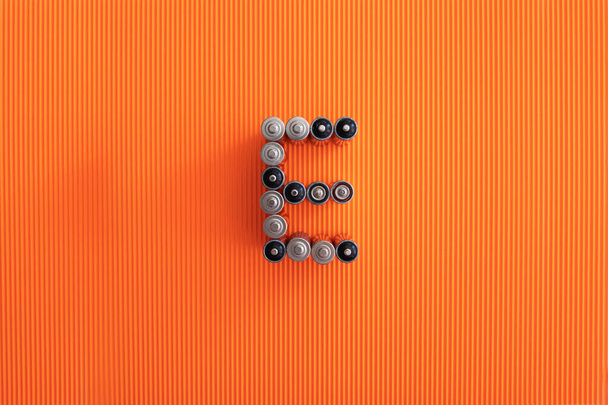 The letter E (energy) consists of aa batteries on an orange background - Photo, Image