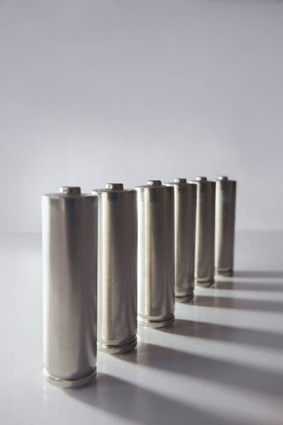 Many gray batteries arranged in a row on a white background - Fotografie, Obrázek