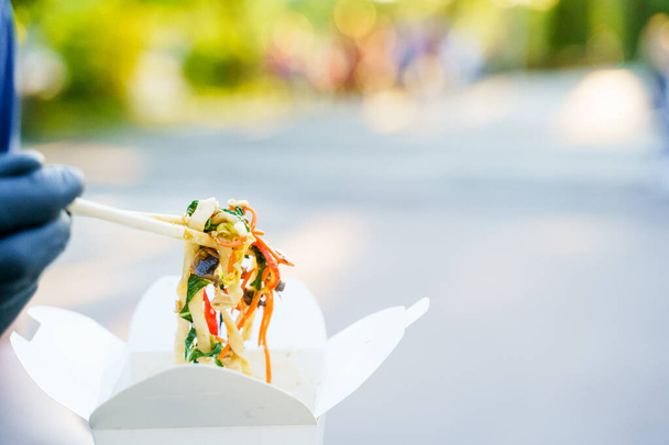 Closeup udon nouilles sur fond flou sort de la boîte blanche. Annoncez pour la livraison du restaurant japonais. Restez à la maison et mangez des nouilles udon avec tempuru, crevettes, sauce soja. Livraison sûre
 - Photo, image