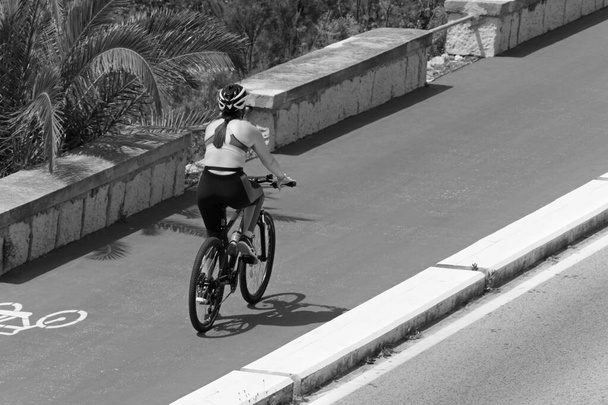 Італія; Сицилія, Марина ді Рагуса (провінція Рагуса), жінка - велогонщик на велосипедній доріжці з велосипедним знаком.  - Фото, зображення