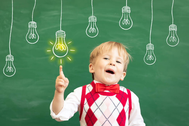 Bright idea! Funny child student pointing finger up! Happy kid against green chalkboard. Online education and e-learning concept. Back to school - Foto, afbeelding