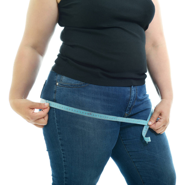Overweight unhappy young woman measuring her hips, isolated over white background. Overeating xxl size woman with measuring tape - Fotoğraf, Görsel
