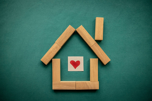 Σπίτι από ξύλινα μπλοκ με μια κόκκινη καρδιά μέσα σε ένα μπλε φόντο. Επίπεδο lay, πάνω όψη, αντιγραφή χώρου. - Φωτογραφία, εικόνα
