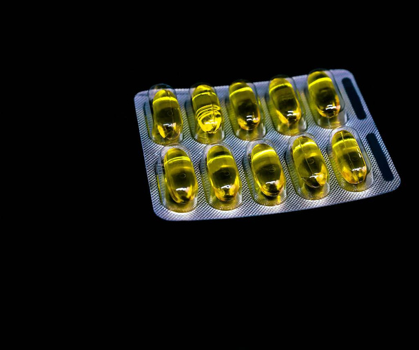 Таблетки или витамины в блистерных пакетах на черном фоне с копировальным пространством. Концепция медицинской аптеки. Селективный фокус
. - Фото, изображение