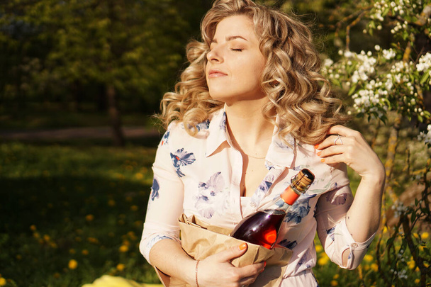 Beautiful young woman holding a blank bottle of wine while having lunch outdoors - Фото, зображення