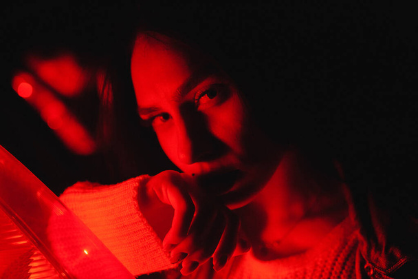 Frau hält seine Hand in der Nähe ihres Kinns im Neonlicht. Frauenporträt - Foto, Bild