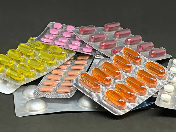 Pile of pills and vitamins in blister packs on dark background with copy space. Medical pharmacy concept. Selective focus - Photo, Image