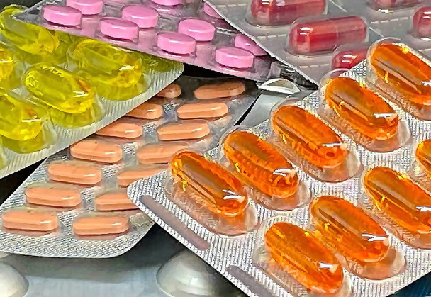 Stos tabletek i witamin w opakowaniach blistrowych na ciemnym tle z miejsca do kopiowania. Koncepcja apteki medycznej. Skupienie selektywne - Zdjęcie, obraz
