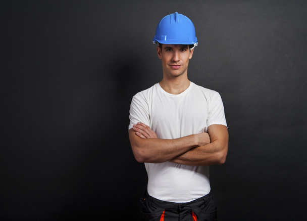 Genç inşaat işçisi kask koyu arka plan üzerinde - Fotoğraf, Görsel
