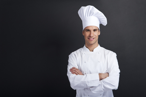 Cozinheiro sorridente contra fundo escuro sorrindo para a câmera
 - Foto, Imagem