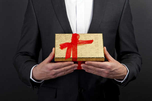 close up of man hands holding gift box over dark background - 写真・画像