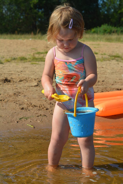 Ένα κορίτσι παίζει στη λίμνη στη ζέστη του καλοκαιριού.  - Φωτογραφία, εικόνα