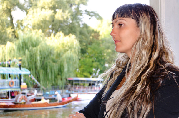 Hermosa mujer junto a un lago con barcos
 - Foto, Imagen