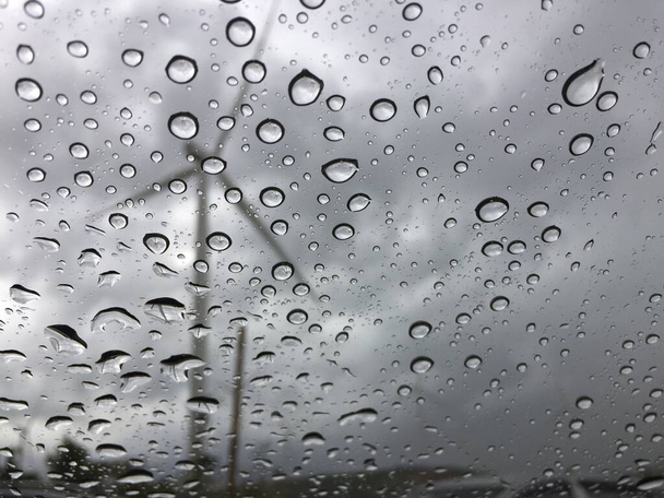 Pluie sur le verre de la voiture L'extérieur offre une vue sur le moulin à vent. Fond triste et solitaire
 - Photo, image