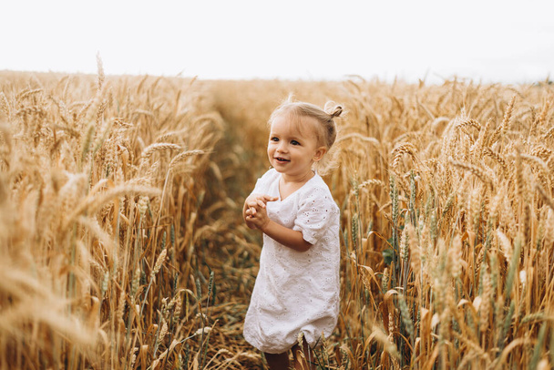 pretty cute baby girl with a beautiful smile wearing summer straw hat in a walk in the  wheat fields. selective focus. family, people concept - Foto, imagen