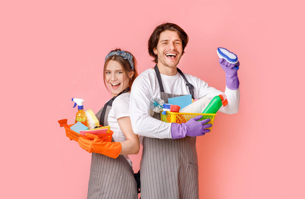 Retrato del equipo profesional positivo de los limpiadores con los suministros del hogar en las manos
 - Foto, imagen