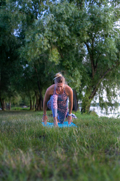 Dar giysili genç, narin kadın nehir kenarında yoga yapıyor. - Fotoğraf, Görsel