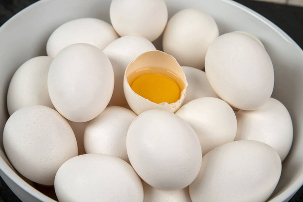 Kuřecí bílá vejce s jedním popraskané otevřené ukazující žloutek - Fotografie, Obrázek