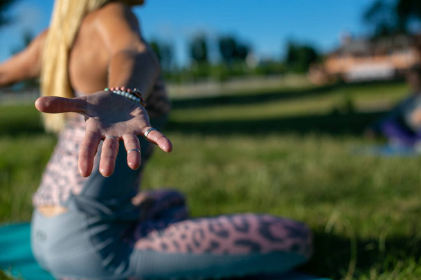 mulher esbelta durante ioga senta-se no asana na grama com os braços afastados
 - Foto, Imagem