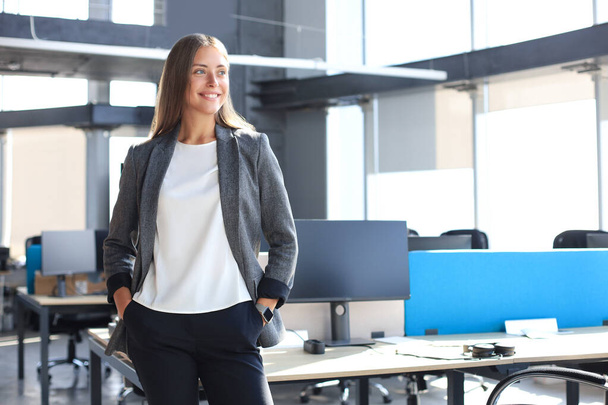 Attractive business woman smiling while standing in the office - Photo, Image