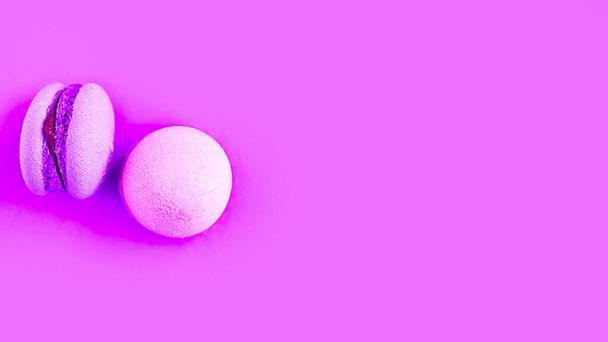 Pink sweet macaroons on purple background. Copy space for the text. Minimal concept - Zdjęcie, obraz