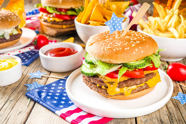 Celebrazione del giorno dell'indipendenza, 4 luglio. Festa commemorativa tradizionale americana Picnic patriottico con hamburger, patatine fritte e snack, Picnic estivo USA e barbecue concetto, Vecchio sfondo in legno
  - Foto, immagini