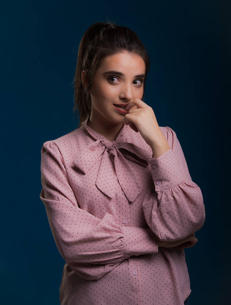young beautiful brunette model in pink sweater,blue background on the back,caressing looks very sweet camera,posing in studio, - Φωτογραφία, εικόνα