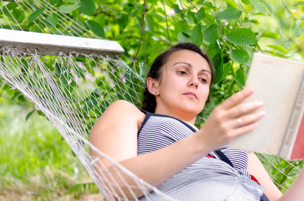 Woman reading whilst relaxing in a hammock - Photo, Image