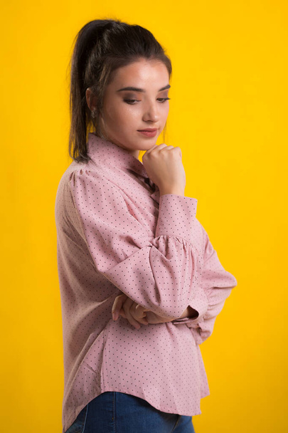 young beautiful brunette model in pink sweater,blue background on the back,caressing looks very sweet camera,posing in studio, - Fotó, kép