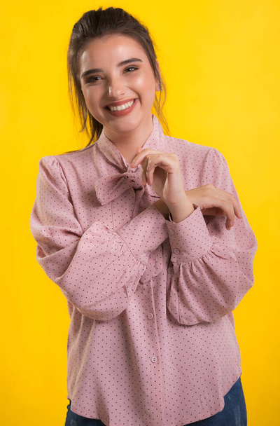 young beautiful brunette model in pink sweater,blue background on the back,caressing looks very sweet camera,posing in studio, - Zdjęcie, obraz