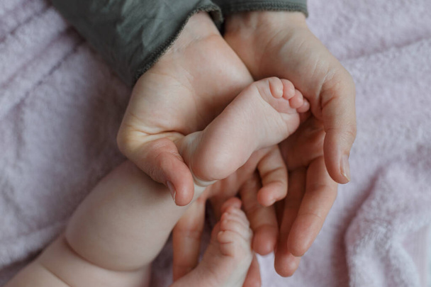 Pies de bebé en manos de madre. Mamá y su hijo. Masajista masajeando el pie de un bebé. Concepto de familia feliz. Hermosa imagen conceptual de la maternidad
 - Foto, Imagen