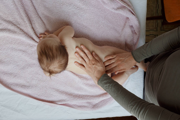 madre fa schiena e un massaggio ai piedi a un neonato. cura della madre. stile di vita sano
. - Foto, immagini
