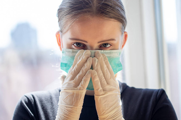 Die junge Frau trägt Operationsmaske und Schutzhandschuhe. Konzept zum Ausbruch von Covid-19-Pandemien - Foto, Bild