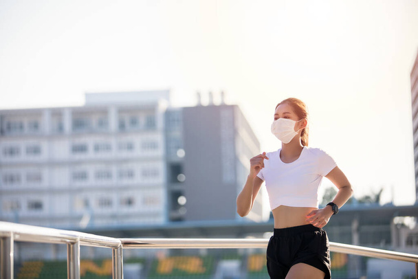 Asiática joven fitness deporte mujer corriendo y ella lleva una máscara para la protección de polvo y la contaminación y la protección del virus de la gripe, gripe, coronavirus en la ciudad
  - Foto, Imagen