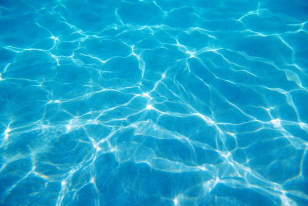 Unter Wasser. Sonneneinstrahlung am Boden des Sitzes. Wellen unter Wasser und Sonnenstrahlen, die durchscheinen. Tieftürkisblaues Meer. Ozean. Transparentes Wasser und Licht am Sand. - Foto, Bild