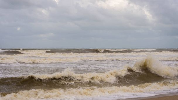 Grote golven raakten Batu Buruk Beach in Kuala Terengganu tijdens het moessonseizoen. Sterke wind uit de oceaan raakte de kustlijn hard. Donkere en bewolkte wolkenachtergrond. Gevaarlijk om met de zee te spelen. Stormachtige zee. - Foto, afbeelding